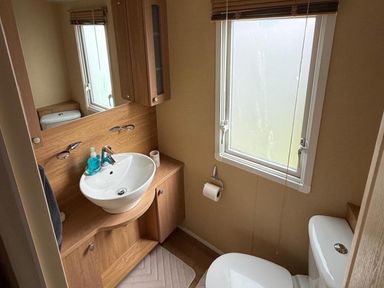 A bathroom with sink, toilet, and window at 2-Bed Caravan, Sleeps 6 w/ Parking, No Pass Needed