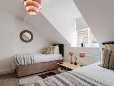 A bedroom with two beds and a side table at Licatas Apartment Cirencester Cotswolds Sleeps 6
