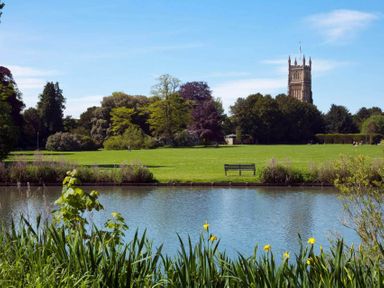 A view of a park with a river and a tower at Licatas Apartment Cirencester Cotswolds Sleeps 6