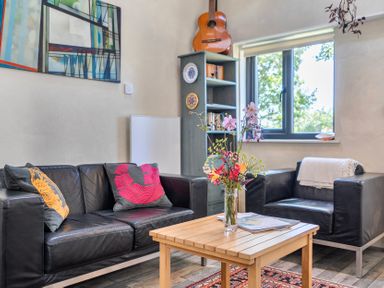 A living room with a sofa, table, bookshelf, and window at Little Linney Sleeps 2 Garden Parking Wifi Hartland