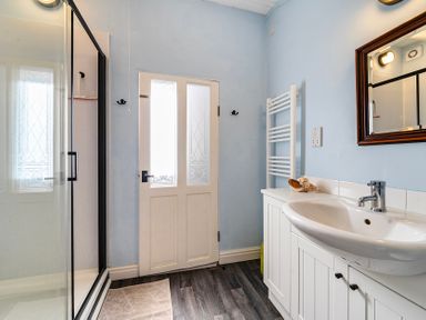 A bathroom with a shower, sink, and door at Little Linney Sleeps 2 Garden Parking Wifi Hartland