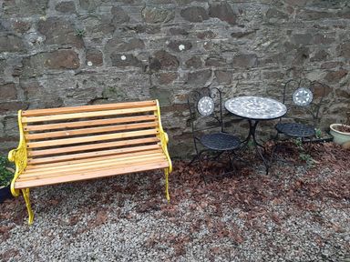 A garden with a wooden bench and a table with two chairs at Ground Floor Cornish Retreat Free Parking Bodmin
