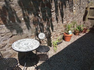 A garden with a table and chair near a stone wall at Ground Floor Cornish Retreat Free Parking in Bodmin