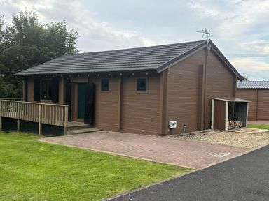 A lodge with a deck and storage shed at Pet Friendly - Lodge at Riverview Holiday Park, Mangerton near Newcastleton