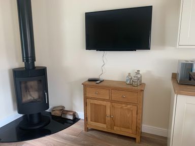 A living room with a wood stove and a television at TBC