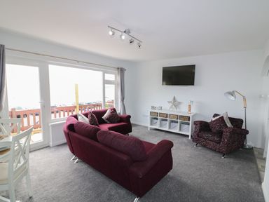 A living room with a sofa and an armchair at The Cartwheel in Amroth