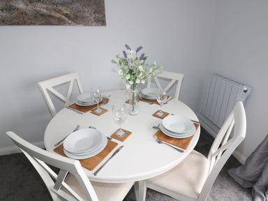 A dining room with a round table set for four at The Cartwheel in Amroth