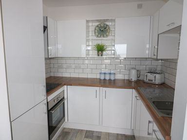 A kitchen with cabinets, oven, sink, kettle and toaster at The Cartwheel in Amroth