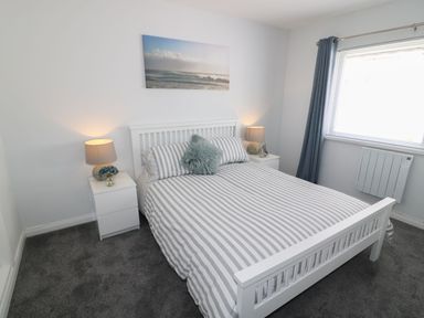 A bedroom with a bed and nightstand at The Cartwheel in Amroth