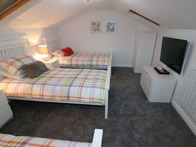A bedroom with two single beds and a television at The Cartwheel in Amroth