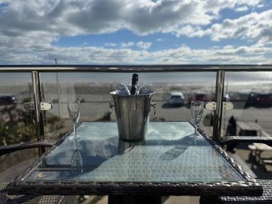 A balcony with a champagne bucket and glasses overlooking the beach at The Cartwheel in Amroth