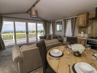 A living room with dining table and sofa at The Dorchester at Bay View in New Quay
