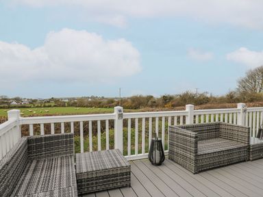 An outdoor seating area with furniture and a view of fields at The Dorchester at Bay View Maen-y-groes near New Quay