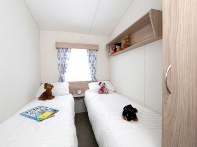 A bedroom with twin beds and toys at Tide’s Reach - Hayling Island