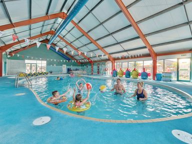 An indoor swimming pool with children and adults playing with beach balls at Tide’s Reach - Hayling Island