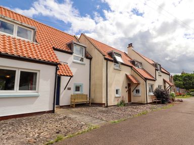 A row of houses with tiled roofs and a bench outside at Sarah's Cottage in 