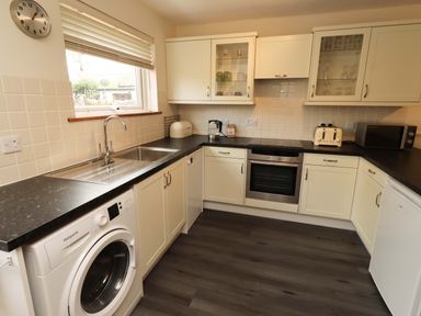 A kitchen with appliances and cabinets at Sarah's Cottage