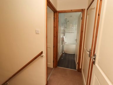 A bathroom with a bathtub and towel rack seen from a hallway at Sarah's Cottage