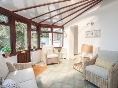 A conservatory with seating and plants at Bryn Llifon in Pentraeth