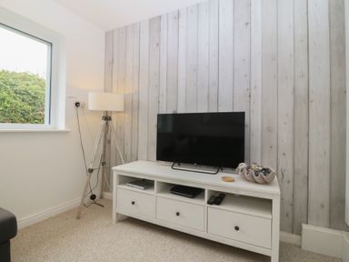 A living room with a TV and lamp at Red Wharf Retreat in Red Wharf Bay near Benllech