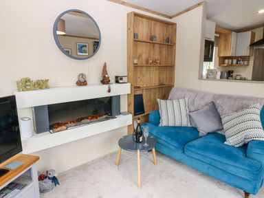 A living room with a blue sofa and a fireplace at Plot 41 High Hesket near Armathwaite