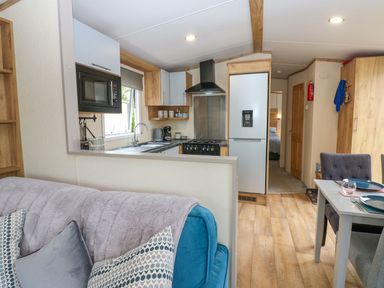 A kitchen with a stove, fridge, and dining area at Plot 41 High Hesket near Armathwaite