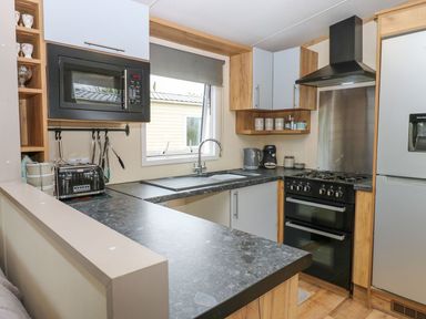 A kitchen with a microwave, stove, and sink at Plot 41 High Hesket near Armathwaite