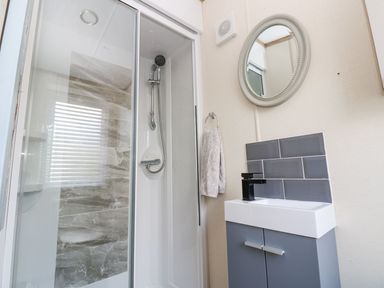 A bathroom featuring a shower, sink with cabinet, and a mirror at Plot 41 High Hesket near Armathwaite