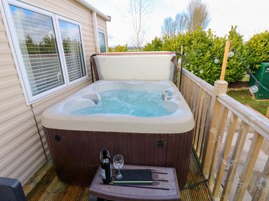 An outdoor hot tub with wine on a table at Plot 41 High Hesket near Armathwaite