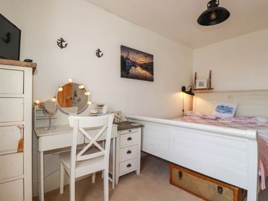 A bedroom with a bed and dressing table at Stones Throw in Mevagissey