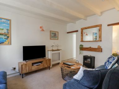 A living room with a television and decorative items at Stones Throw in Mevagissey