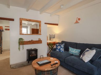 A living room with a sofa and fireplace at Stones Throw in Mevagissey