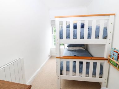 A bedroom with a bunk bed and books on the wall at Llys Awen in Caernarfon