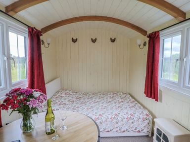 A bedroom with a bed and table with wine at Shepherds Hut at East Hill Pride Four Elms Hill Nr. Sidmouth