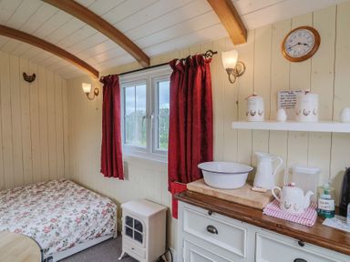 A bedroom with a bed, window, and shelf at Shepherds Hut at East Hill Pride, Four Elms Hill Nr. Sidmouth