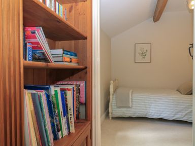 A bedroom with a bed and bookshelf at 2 The Gardens Lechlade