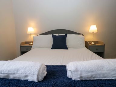 A bedroom with a bed and lamps at Courtyard Cottage in Cartmel