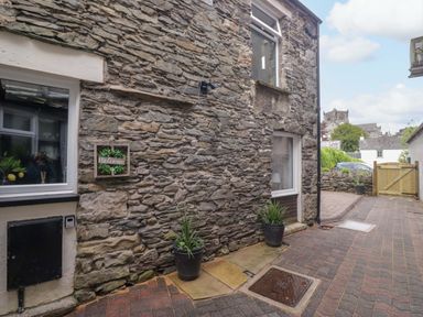 An outdoor area with a stone wall and plants at Courtyard Cottage in Cartmel