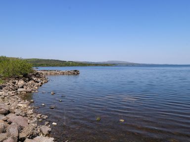 A shoreline with rocks and water at Mayfly Cottage
