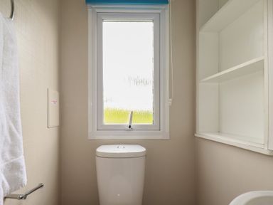 A bathroom with a toilet and window at Tucked Away in Newquay