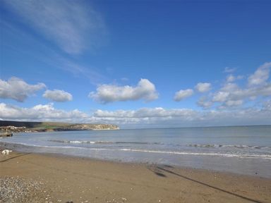 A beach with sand and water under a blue sky at Little Wickers in Wareham