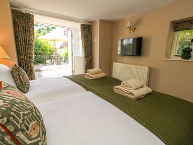 A bedroom with twin beds and a view to a garden at Little Wickers in Corfe Castle