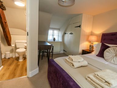 A bedroom with a bed and adjoining bathroom at Little Wickers Corfe Castle