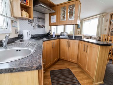 A kitchen with a sink, stove, kettle, and cupboards at Winchester - 478 Abergele