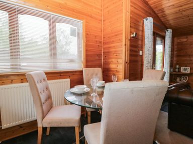 A dining room with a glass table and chairs at 89 Ambleside in White Cross Bay