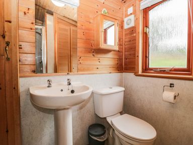 A bathroom with a sink, toilet, and window at 89 Ambleside in White Cross Bay