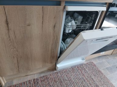 A kitchen with an open dishwasher containing dishes in Porthcurno 5, Perranwell near Goonhavern