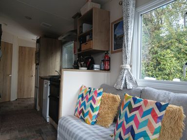 A living room with a couch and kitchen appliances at Porthcurno 5 Perranwell near Goonhavern