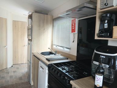 A kitchen with a sink, stove, and refrigerator at Porthcurno 5 Perranwell near Goonhavern