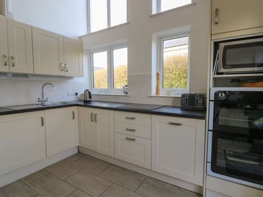 A kitchen with cabinets, sink, kettle, and toaster at Tegfan in Newport